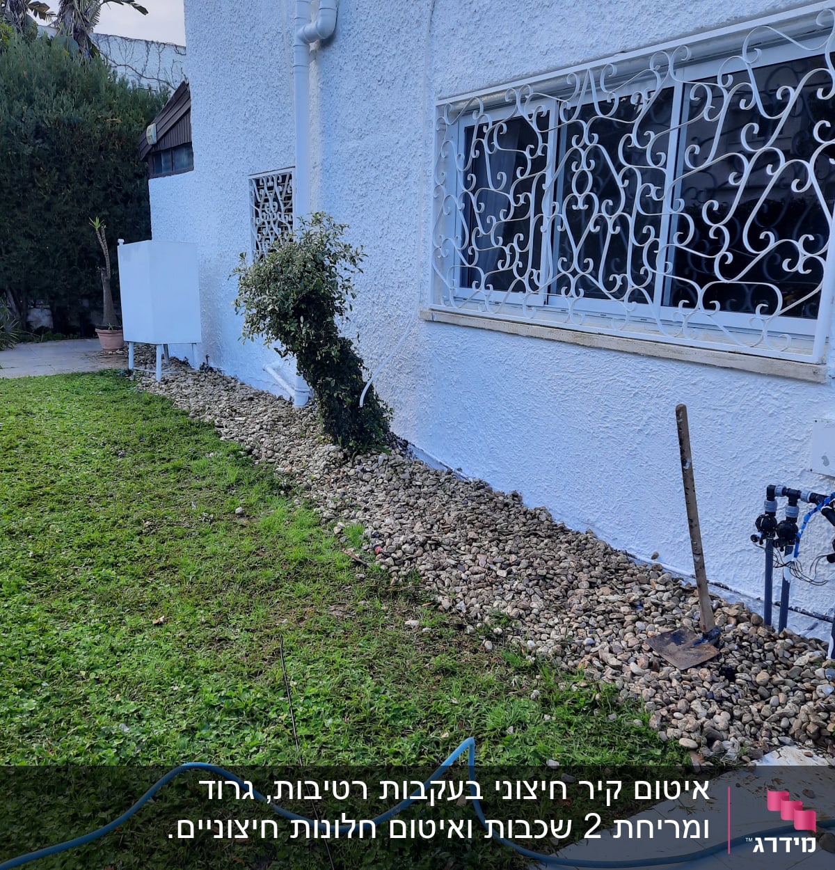 צינור מים כחול על דשא ליד קיר לבן